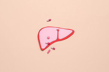 Pink paper liver with pills on beige background