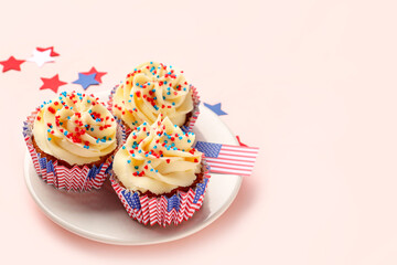 Plate with tasty patriotic cupcakes and flag of USA on pink background. American Independence Day