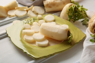 Plate with fresh daikon radishes on white background