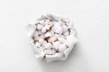 Cotton flowers in basket with towel on white background