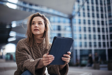 Portrait of young fashionable woman in a city with digital tablet.