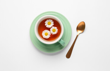 Cup of natural chamomile tea and flowers on white background