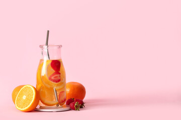 Bottle of infused water with orange slices on pink background