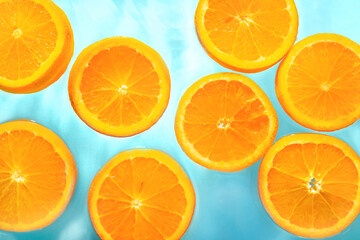Slices of fresh orange in water on blue background