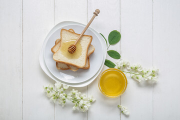 Composition with sweet honey, acacia flowers and toasts on light wooden background