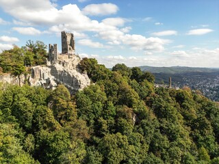 Fototapeta na wymiar Drone shot of the Burg Drachenfels castle on a rocky hill surrounded by green vegetation in Germany