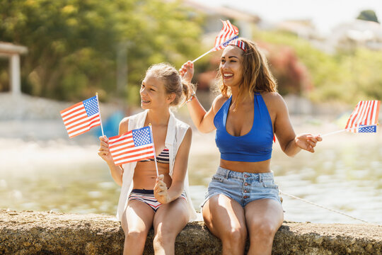 Two Female Friends With US National Flag Enjoying A Summer Vacation