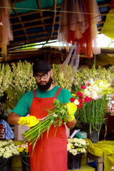 Happy mature man feeling proud of her flowers while working in plant nursery and looking at camera