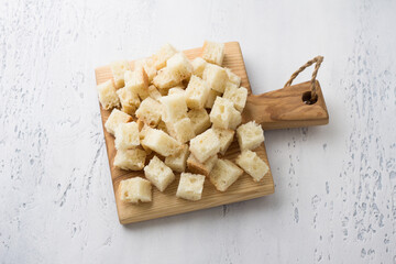 Wooden board with diced bread, croutons cooking on light blue tabletop, top view