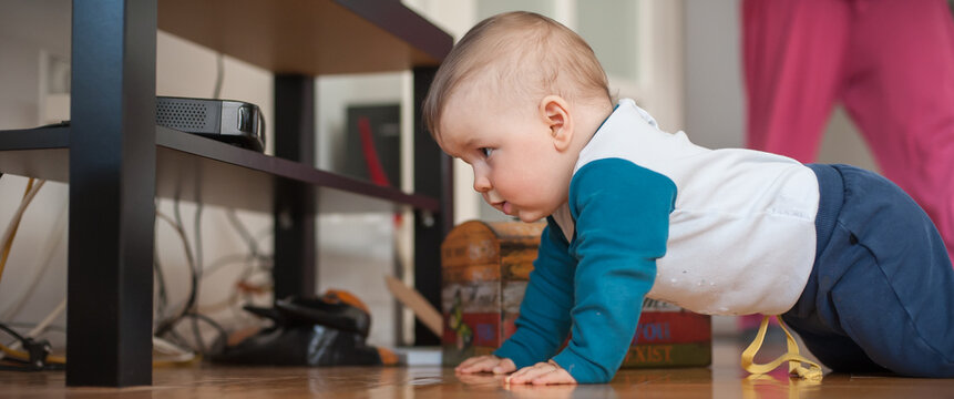 Cute baby boy crawls on the home floor, explore the world and things around him. Love and family emotion