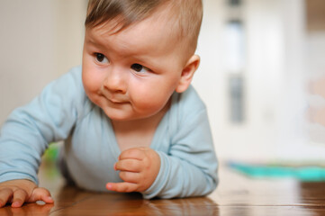 Naklejka premium Cute baby boy crawls on the home floor, explore the world and learn to move. Love and family emotion