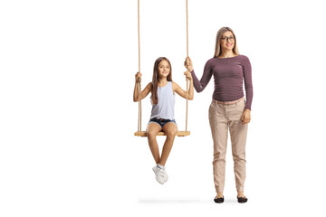 Mother standing next to a girl on a swing