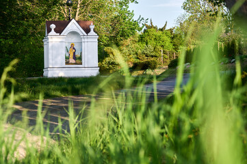 A roadside shrine among the grass against the background of tree