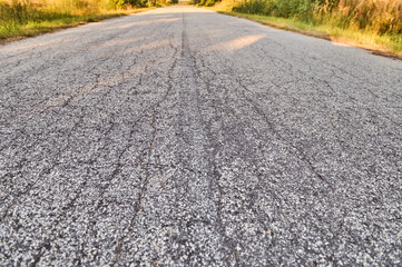 The gray cracked asphalt of the paved road