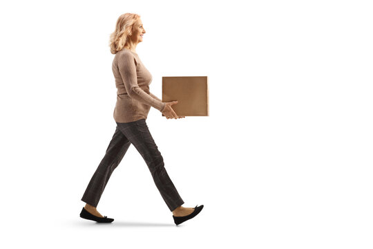 Full length profile shot of a mature woman walking and carrying a box