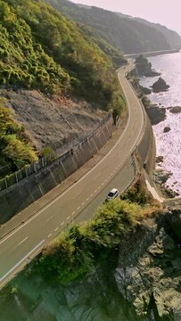 Vertical aerial view of a beautiful scenic road along the wild coastline in Ehime, Ozu, Nagahamacho Kushuu, Japan.