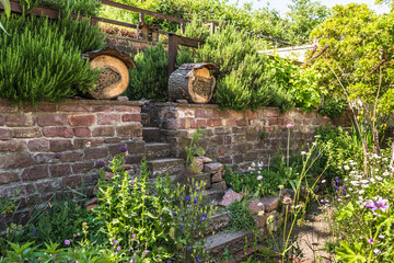 Natural garden with native plants, stone wall and insect hotels, bug hotels, insect houses. Natural...