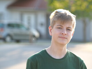 Outdoor portrait of a friendly caucasian blue-eyed teenager in a green t-shirt - 607534750