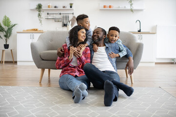 Energetic multiethnic children in jeans clothes talking to relaxed adults while staying indoors on...