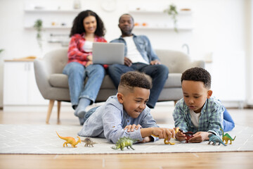 Selective focus of playful multicultural kids lying on floor coverd with carpet while relaxed...