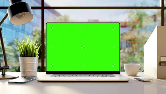 A laptop with an empty green screen on the desk in the office, with trees  swaying in the wind and office buldings in the background. Looped video. 3d render