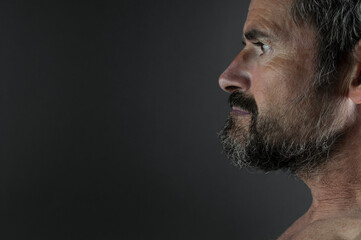 Portrait of aged serious beard man close up on black background