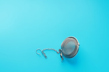 Closed metal tea strainer on bright blue background