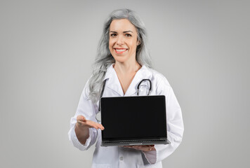 Doctor Lady Showing Laptop Blank Screen Advertising Website, Gray Background