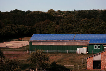 Fototapeta na wymiar Warehouse with solar panels on the roof. Nature-produced energy. Sun-produced energy. Photovoltaic systems on the barn house in the countryside. Semiconductor technology. Carbonless footprint.