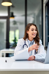 A busy female doctor having an online video call with colleagues over a laptop.