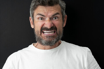 Obraz premium Portrait of indignant beard man in white t-shirt close up on black background