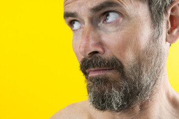 Obraz premium Portrait of astonished beard man on yellow background