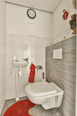a small bathroom with red rugs on the floor and white tiles on the walls, along with a toilet
