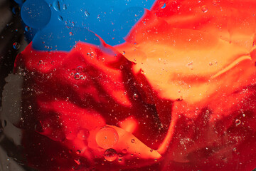 Drops of oil in water on a red and blue background, abstraction