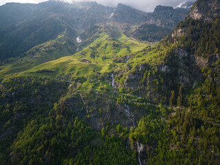 Sommer in den Alpen mit grünen Wiesen, Wasserfällen und Gletschern