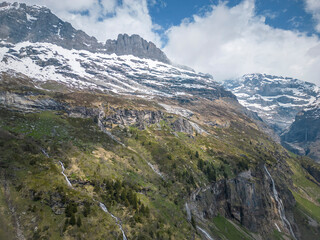 Sommer in den Alpen mit grünen Wiesen, Wasserfällen und Gletschern
