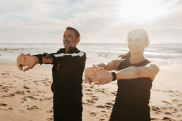 Smiling mature european man and woman doing arm exercises, stretching and warm-up