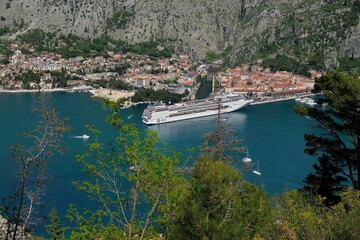 View of Bay of Kotor with buildings of Kotor and standing big cruise ship by coast from tourist rail on Vrmac Peninsula, with the highest peak Sveti Ilija. Montenegro, Balkans