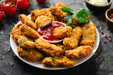 Delicious Crispy Fried Breaded Chicken Breast Strips with Ketchup on Dark Background