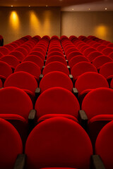 Algumas fileiras de poltronas na cor vermelha em um teatro vazio.