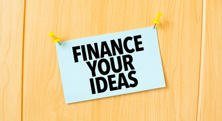 FINANCE YOUR IDEAS sign written on sticky note pinned on wooden wall