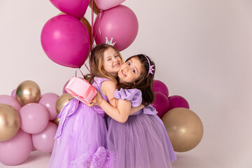 Birthday celebration concept, little princess in lilac dresses, cheerful preschool girl party, two girls with balloons on the background, copy space © Irina Mikhailichenko