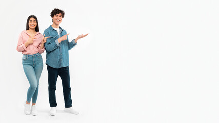 Fototapeta premium Cheerful Couple Showing Copy Space Pointing Fingers Aside, White Background
