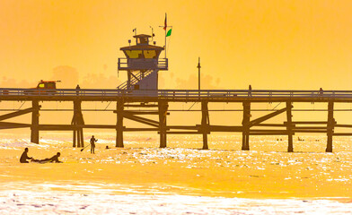 Surfers at San Clemente pier in the golden light of a summer sunset in Southern California - 607561586