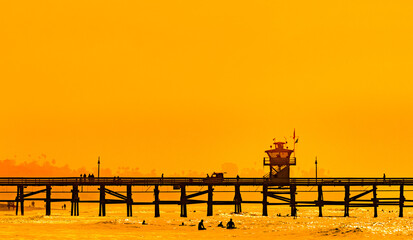 Surfers at San Clemente pier in the golden light of a summer sunset in Southern California - obrazy, fototapety, plakaty