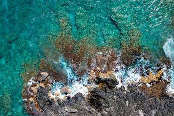 Spectacular Aerial View: Majestic Waves Crashing on Kona's Rocky Coast with Vibrant Reef in Hawaii