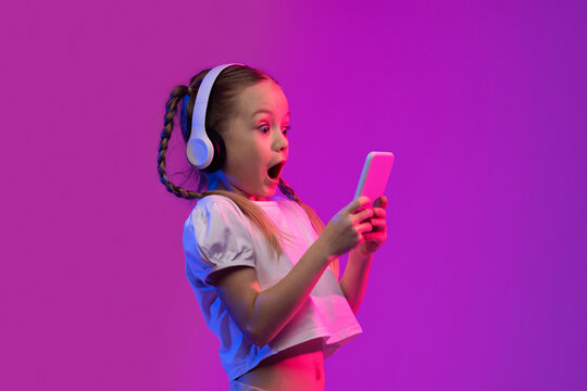 Emotional little girl playing video games on smartphone