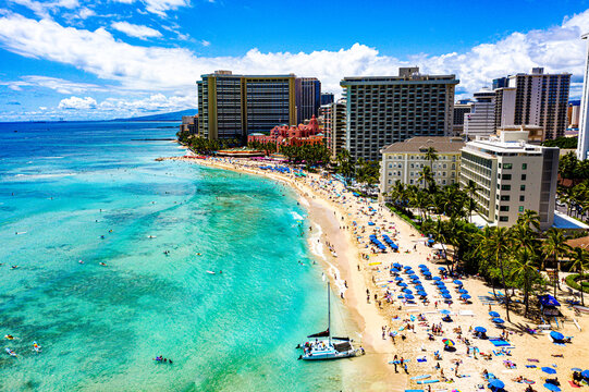Serenity on the Waikiki Coastline: Sailboat, Blue Beach Umbrellas, and Tranquil Views