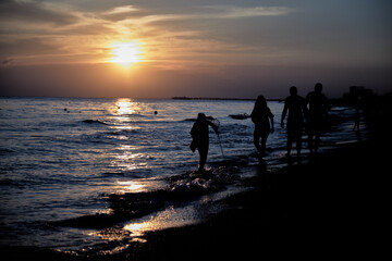 silhouette of a family by the sea at sunset in summer.