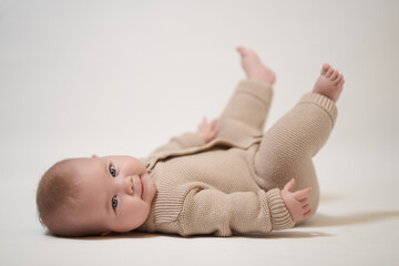 Portrait of a newborn baby on a light background lying on his back with his legs up